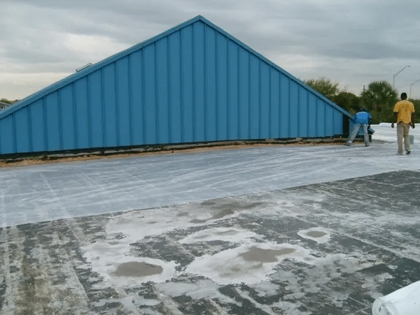 Andros Roofing installers positioning a metal standing seam on the roof